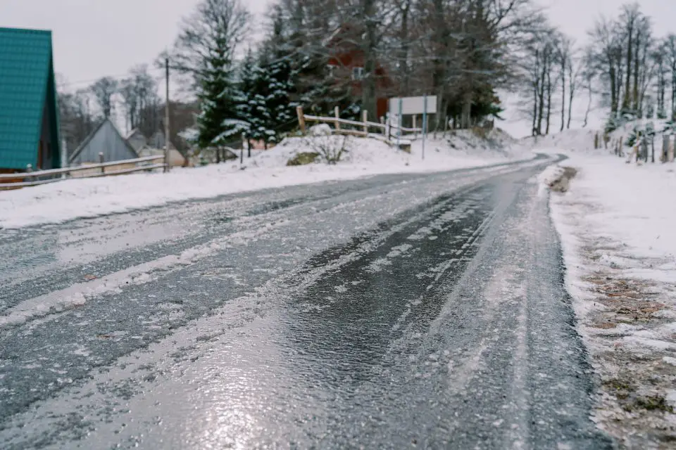 Icy road in snowy rural winter scene.