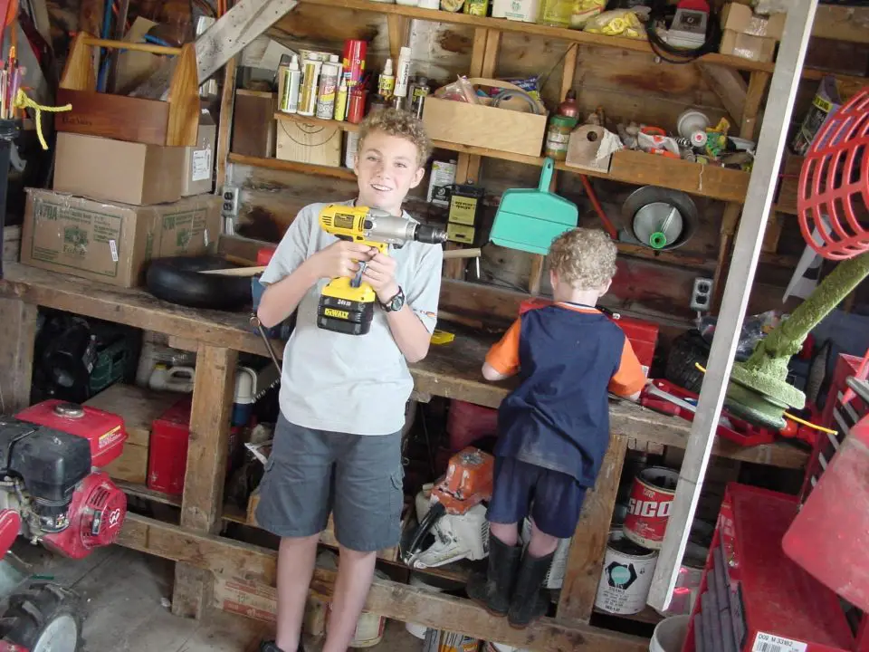 Children playing with drill in workshop.