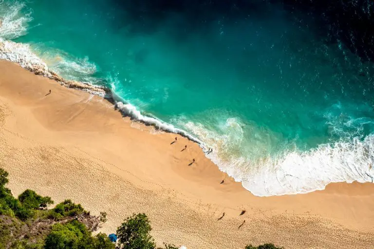 Aerial view of sandy beach with turquoise waves.