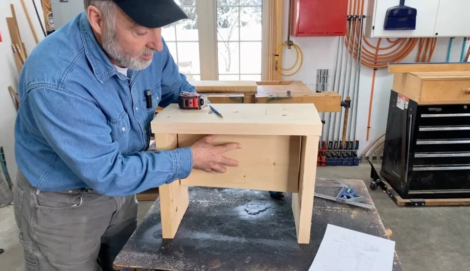 Man building a wooden stool in workshop.