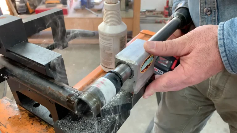 Person cutting metal pipe with power tool.