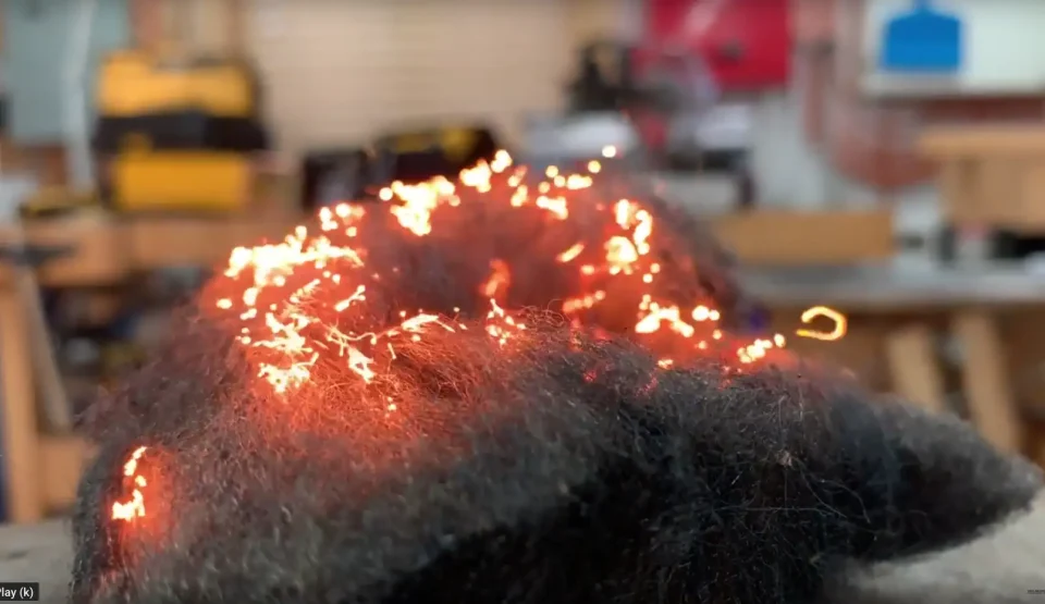 Steel wool glowing with sparks in workshop.