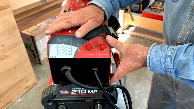 Adjusting settings on welding machine in workshop.