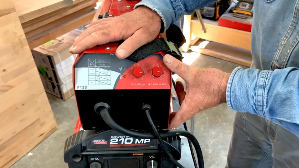 Adjusting settings on welding machine in workshop.