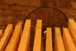 Wooden slats drying with a fan behind.