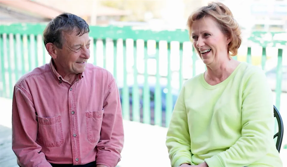 Smiling man and woman sitting together outdoors.