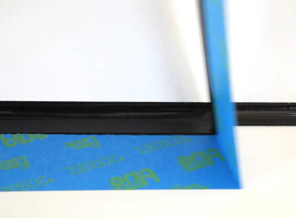 Removing blue painter's tape from a black frame.