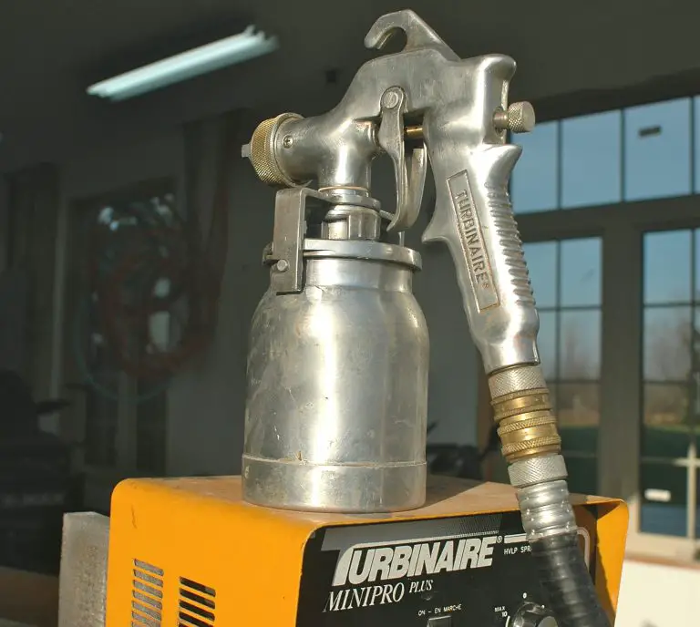 Industrial spray gun on a machine in workshop.