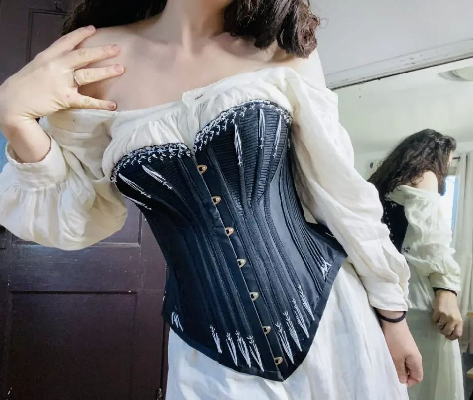 Woman wearing black corset and white dress.