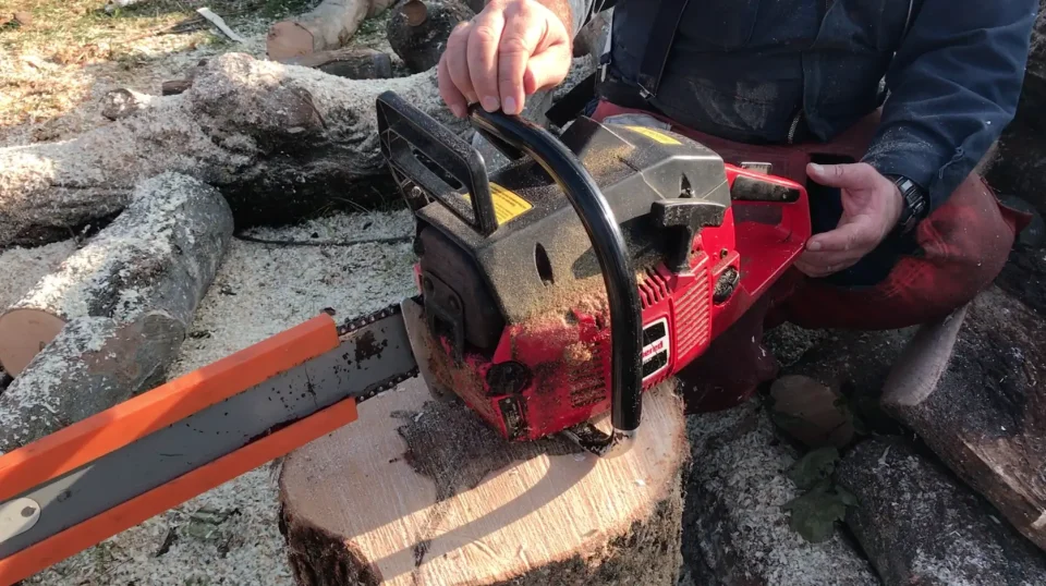 Person using chainsaw on tree stump outdoors.