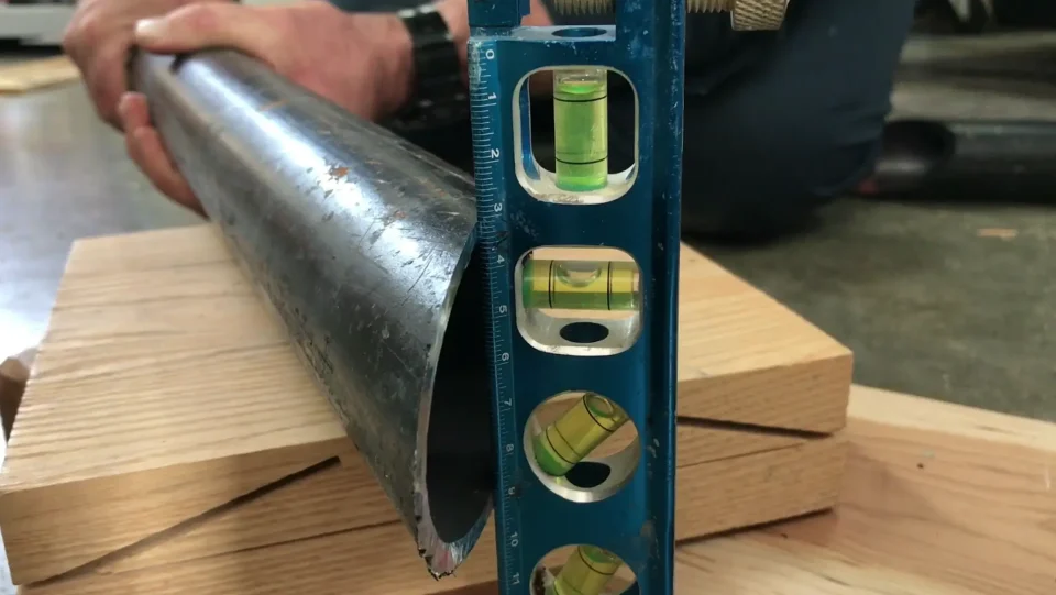 Using level on metal pipe for accurate measurement.