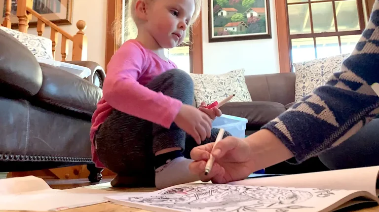 Child colouring pages with crayons indoors