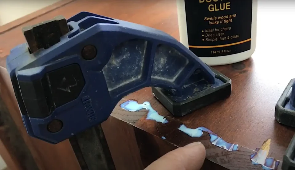 Wood glue and clamp securing furniture repair.