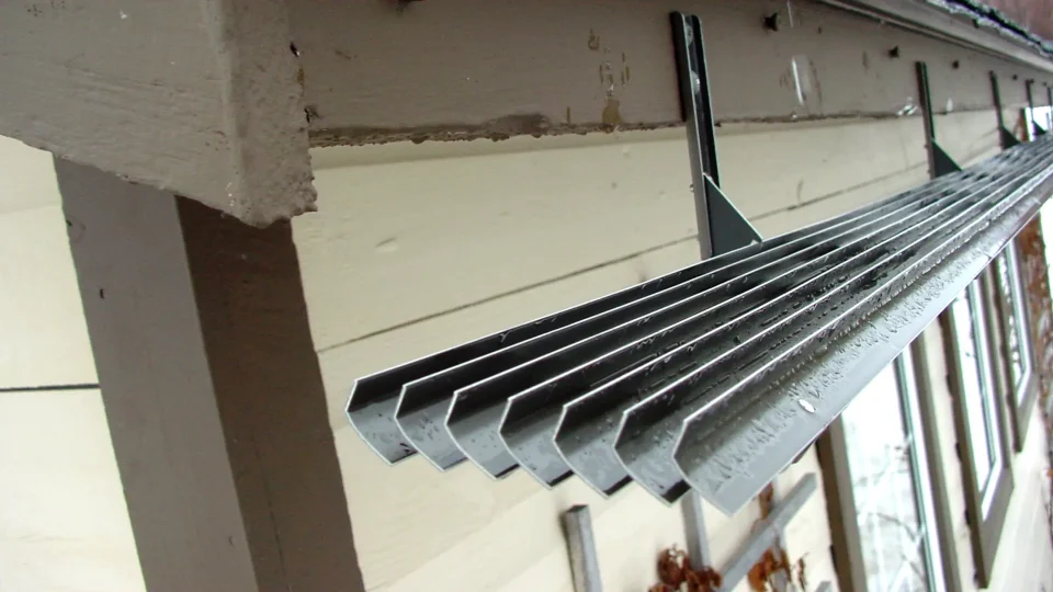 Rain gutter with water droplets on metal surface.