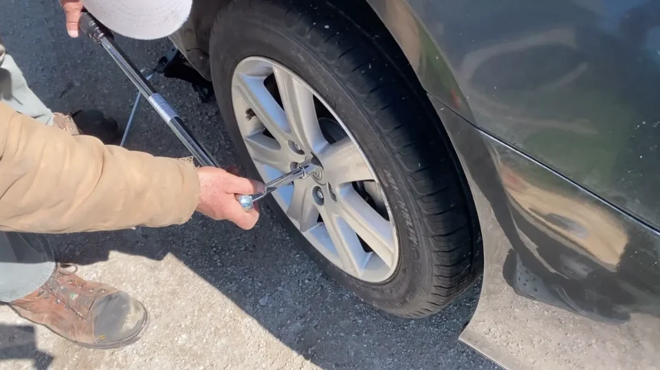 Tightening car wheel lug nuts with a wrench.