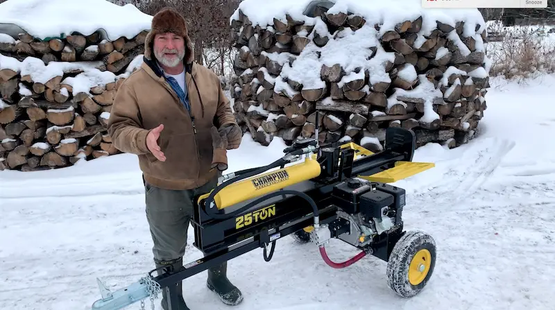 Man with log splitter in snowy landscape.