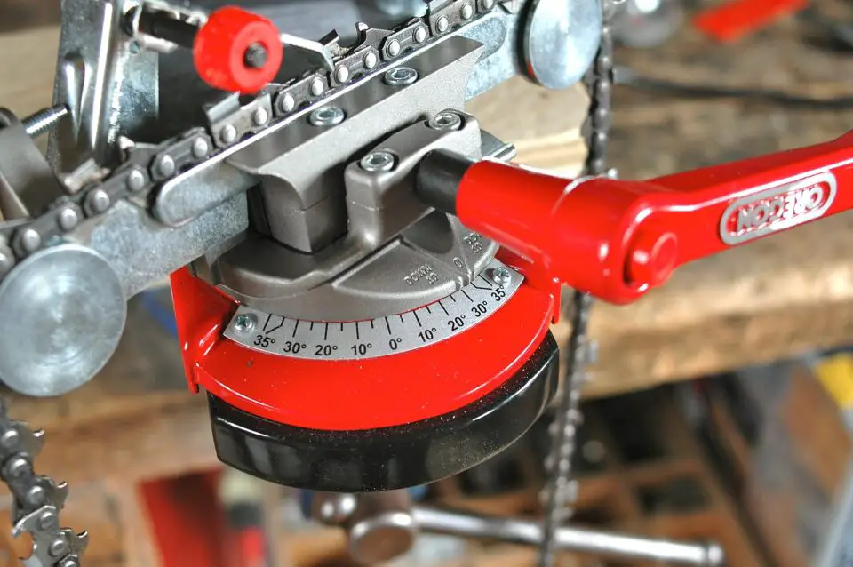 The swivelling base of the sharpener holds the chain at an angle to the spinning abrasive wheel. Most chains are ground at the 30º setting. Use a new chain as a guide for adjusting the sharpener for working on an old chain.