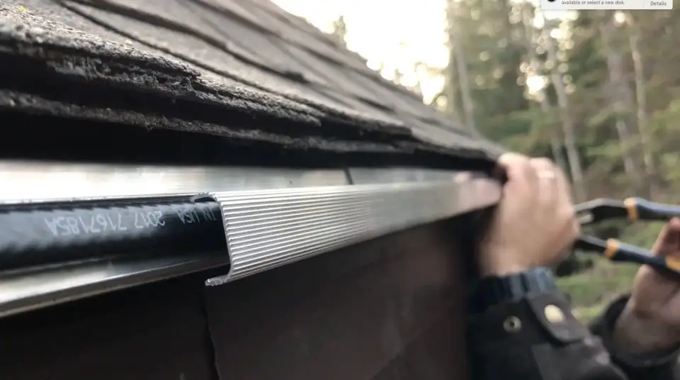 Installing eavestrough on a wooden roof edge.
