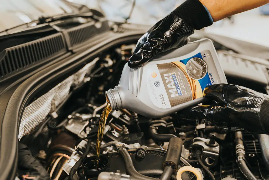 Mechanic pouring oil into car engine