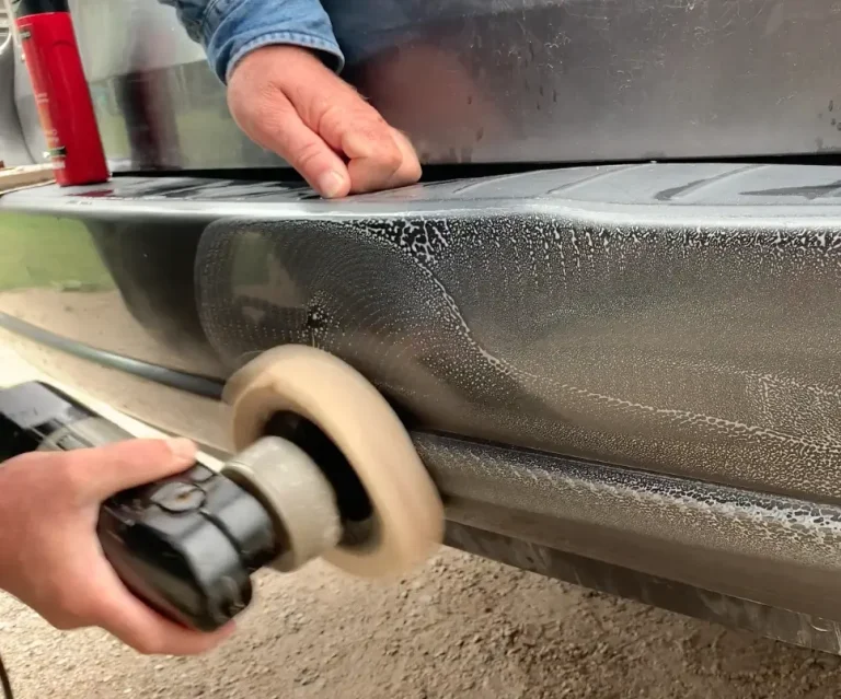 Person polishing scratched vehicle bumper.