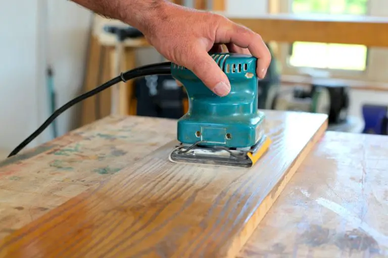 Person sanding wood with electric sander.