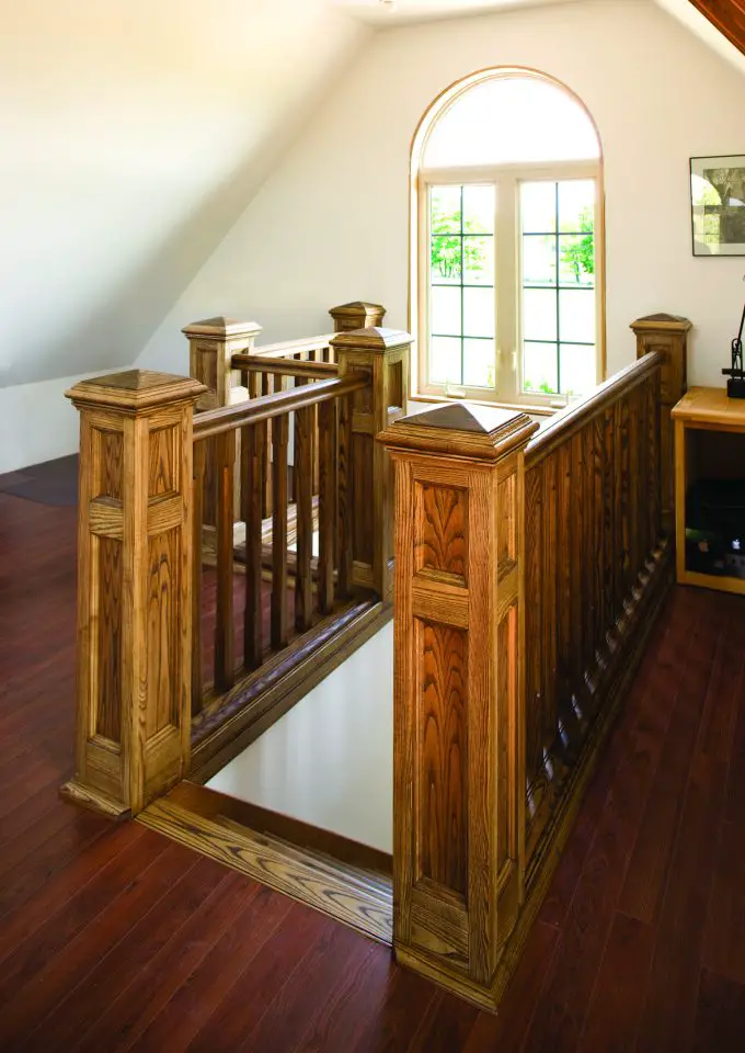 Wooden staircase near large window with natural light.