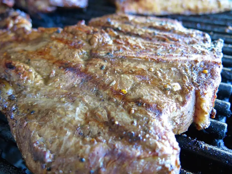 Grilled steak on barbecue grill, close-up view.