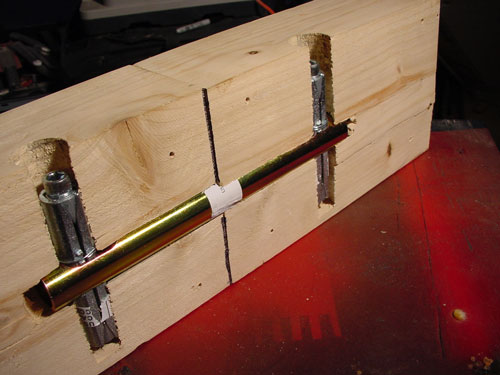 The dark line running down the centre of these pieces of wood is a joint line, and the gold-coloured tube running horizontally spans from one piece of wood to another. The shorter vertical parts have an Allen head bolt that causes expansion and locking when turned.