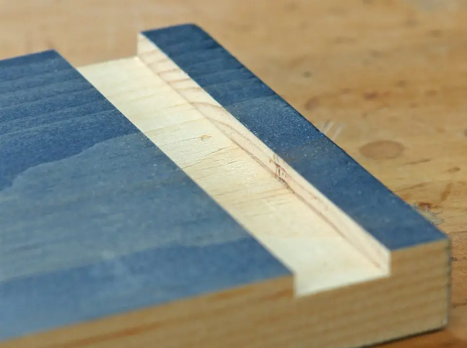 The groove cut here in the wood part stained blue is called a “dado”. It’s a mainstay woodworking joint, and there’s one excellent way to cut many of them accurately.