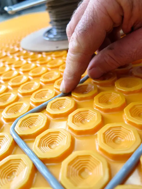 DITRA-HEAT by a company called Schluter is a heated floor system that uses an orange dimpled plastic uncoupling membrane to boost tile reliability and to hold heating cables. The grey wire you see here is what delivers heat, and it snaps into place in the membrane during installation, with tiles going down on top.