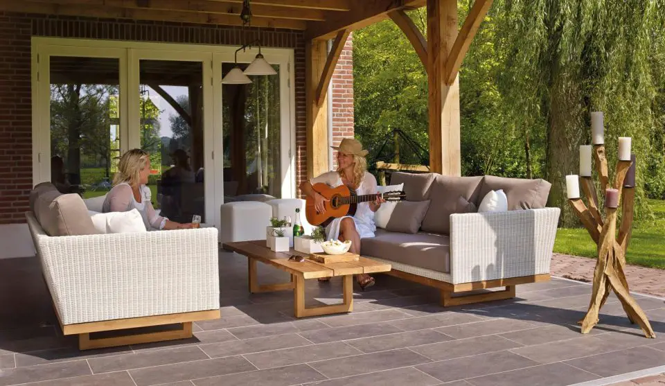 Women relaxing on patio, one playing guitar.
