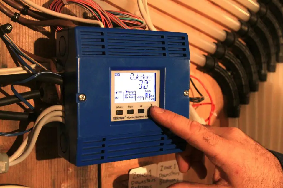 Person adjusting blue temperature control device indoors.