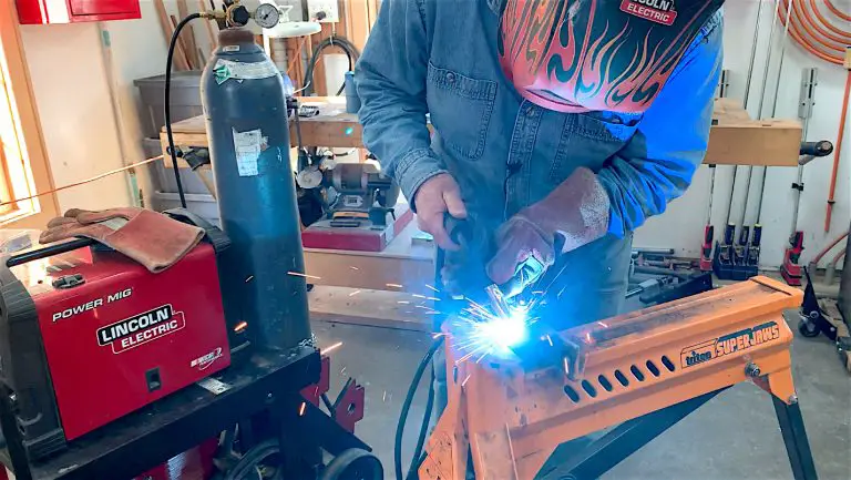 Person welding in a workshop using safety gear.