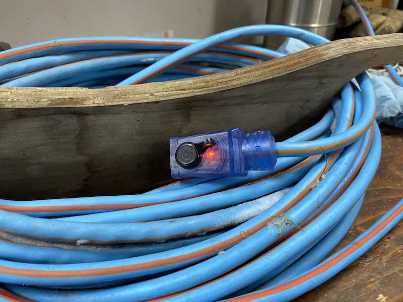 A simple thing, but highly useful. Illuminated cord ends tell you at a glance if you have power. This cord is stored on a 3/4″ plywood cord caddy I cut with a jigsaw.