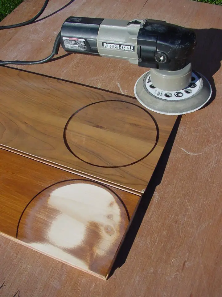 An abrasion test I ran to compare laminate flooring (background) with conventionally finished wood flooring (foreground). Both pieces of flooring had the same amount of time – about 60 seconds – under this 6″ random orbit sander spinning an 80-grit disk.