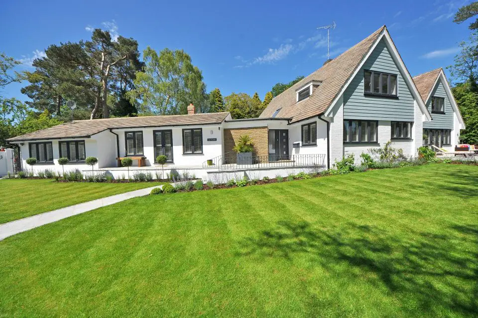Modern house with large green lawn and trees.