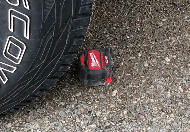 A Milwaukee tape measure just before getting run over by a half-ton pickup truck. Watch the video to see how the tape fared.