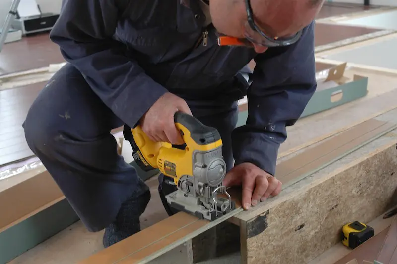 Here I am cutting a piece of laminate flooring with a “top grip” jigsaw. Laminates dull most circular blades very quickly, but jigsaws are another matter. Even a regular blade in a jigsaw can makes dozens of cuts of laminate flooring without getting dull. And the relatively rough cuts by the jigsaw don’t matter because all cut ends of flooring are hidden against walls or under baseboard.