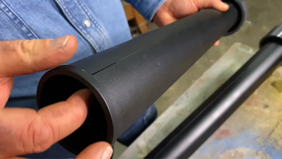 Person examining black plastic pipe for cracks.