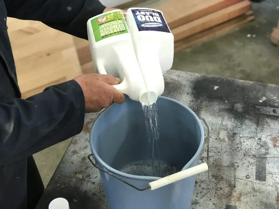 Here I am pouring two parts of an oxygen-based cleaner into a plastic bucket for use. The jug has two separate sides to keep the ingredients separate until ready to use.