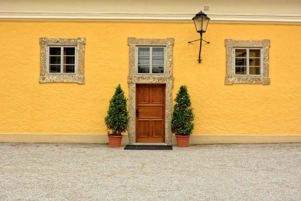 Yellow wall with wooden door and green plants.