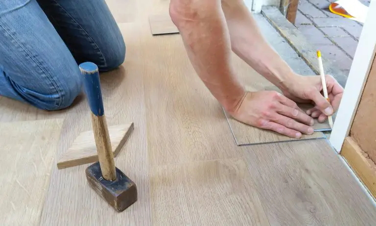 Person measuring and installing laminate flooring.
