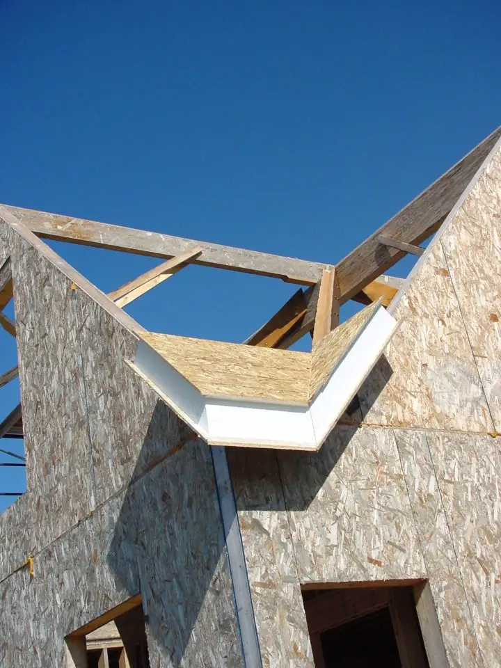 Wooden house frame under clear blue sky.