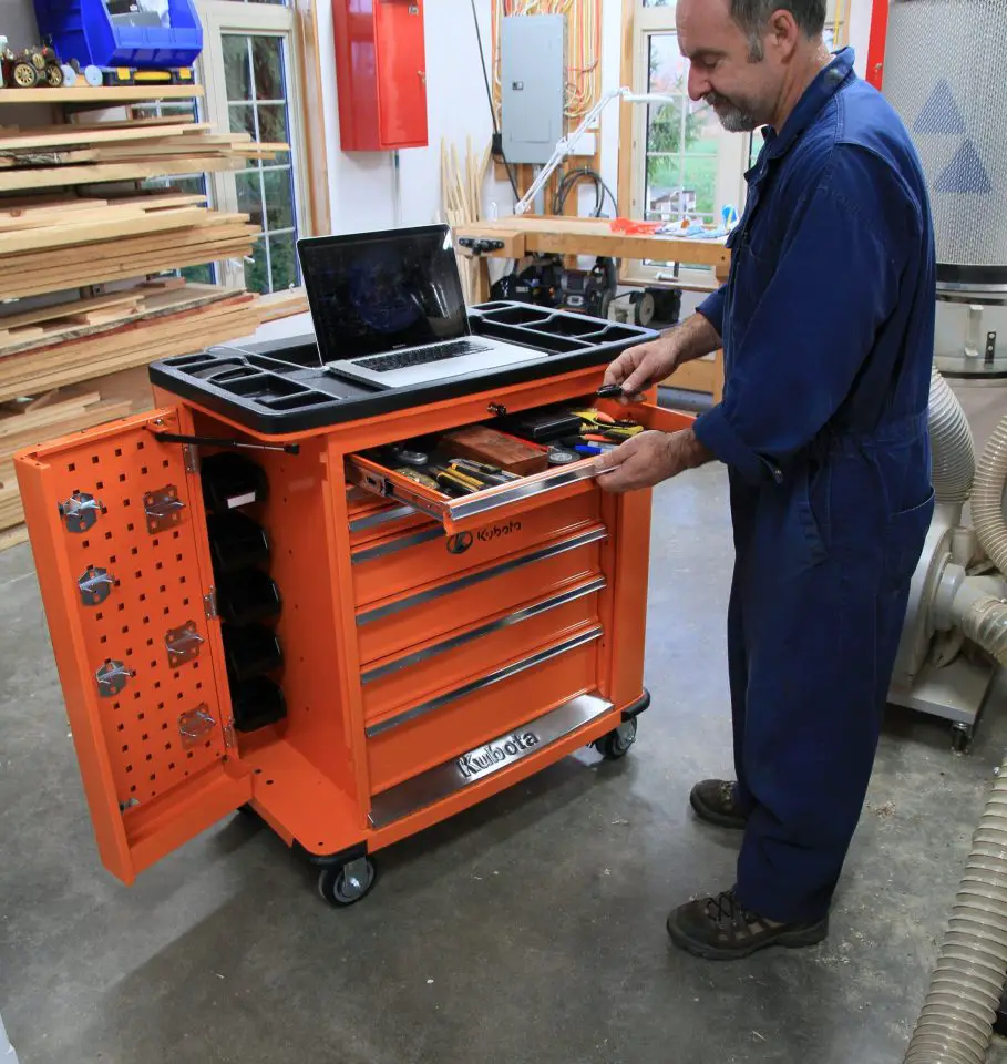 Man organizing tools in orange workshop cabinet.