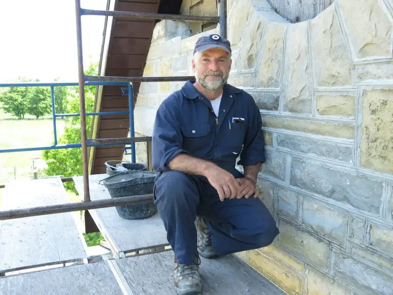 Worker restoring stone building facade on scaffolding.