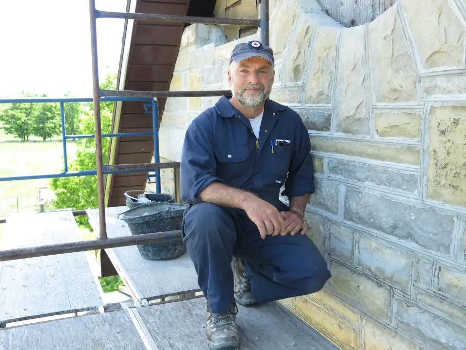 Worker restoring stone building facade on scaffolding.