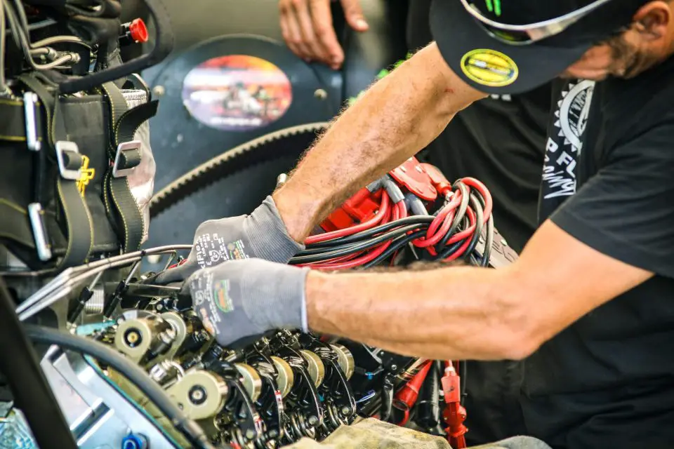 Mechanic working on engine with red cables