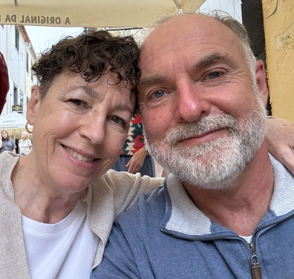 Elderly couple smiling in outdoor setting.
