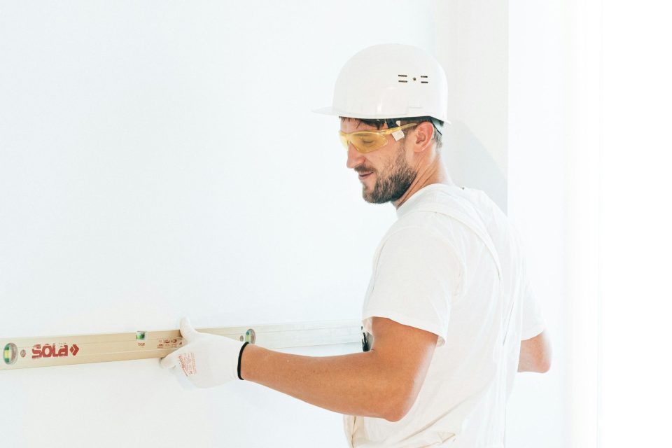 Construction worker using a level on wall