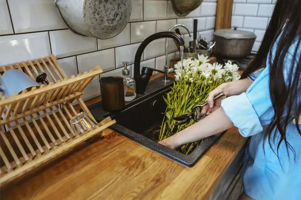 Woman trimming flowers in a sink with a black faucet